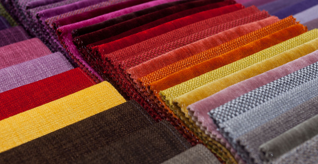 Palette de peintre en bois vue du dessus avec couleurs vives tangerine et corail se prolongeant sur un tissu blanc, symbolisant le processus créatif de personnalisation textile