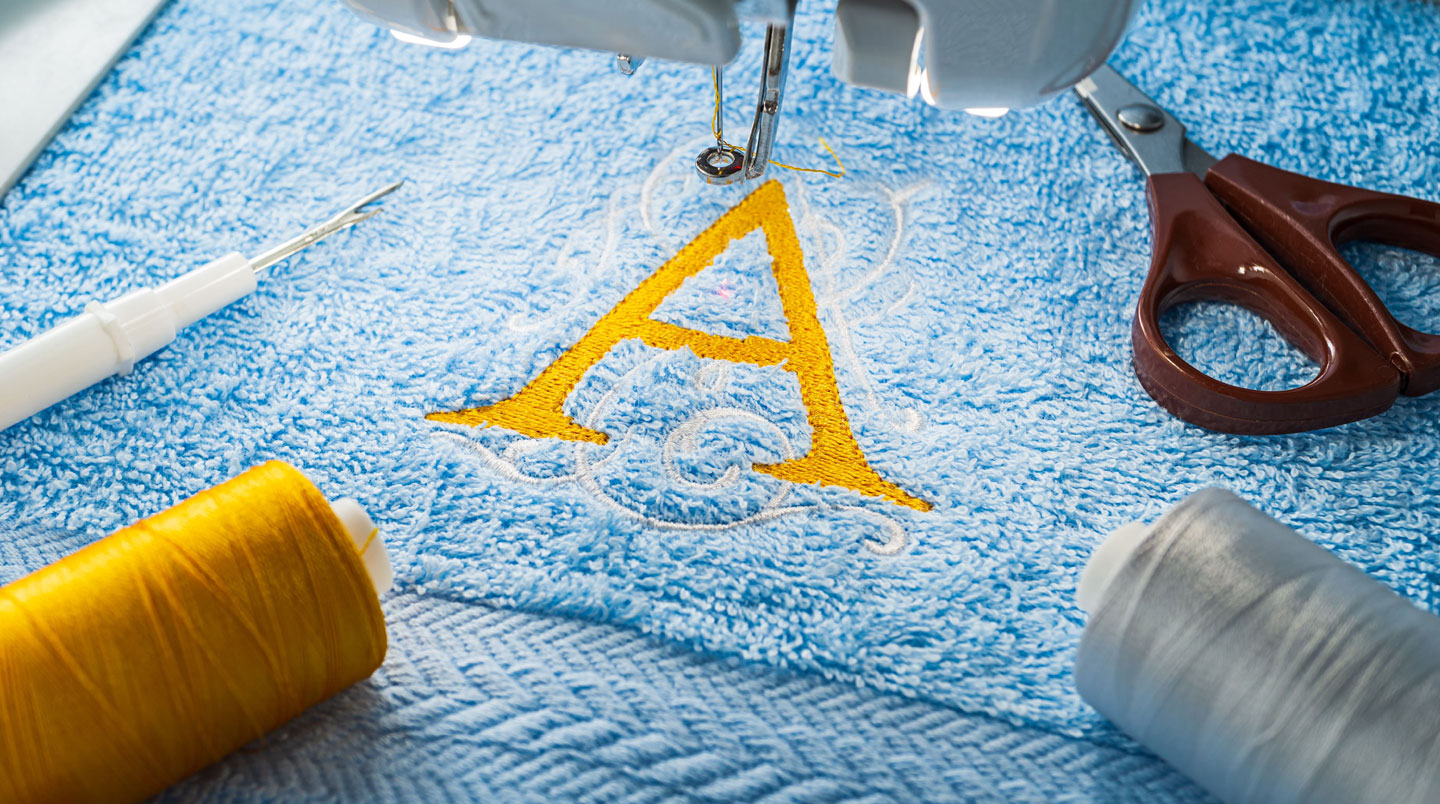 Gros plan texture éponge blanche haute qualité avec broderie logo marine nette démontrant résistance après lavages professionnels